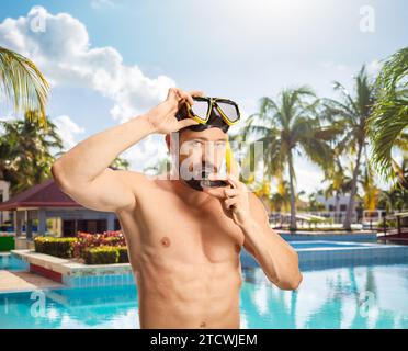 Young man putting on a diving mask by a swimming pool Stock Photo