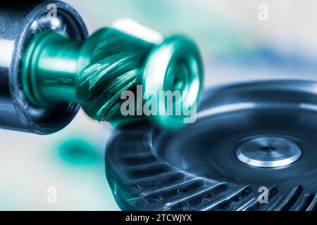 Closeup of rotating interlocking metal cogwheels in artistic blue-green tone. Beautiful motion of perfect meshing circular gear wheel and small pinion. Stock Photo