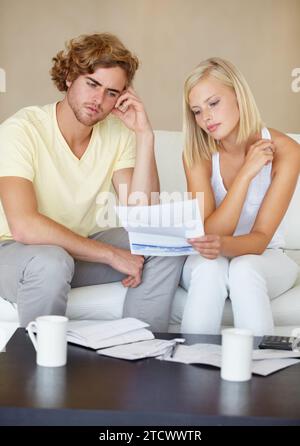 Sad couple, bills and documents stress on sofa in debt, financial planning and budget risk or worry at home. Young woman and man with depression Stock Photo