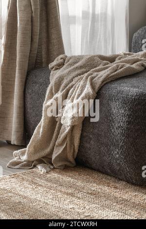 Cozy knitted blanket on a dark grey sofa. Wabi-sabi interior details for decoration Stock Photo
