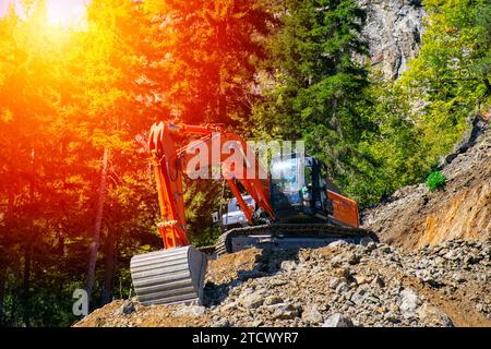 Excavator at the construction site on the slope of a hill against the sunset. Stock Photo