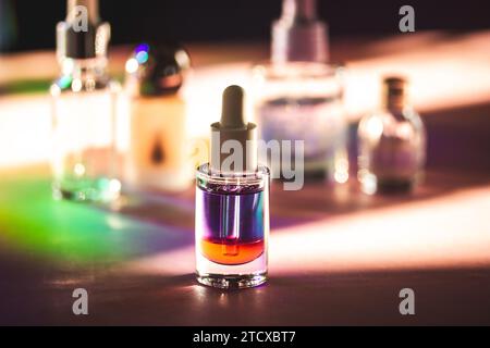 Glass container with red violet liquid. Two-phase cuticle remove oil. Beautician products on a cosmetic table. Self care tools and products in shadow. Stock Photo