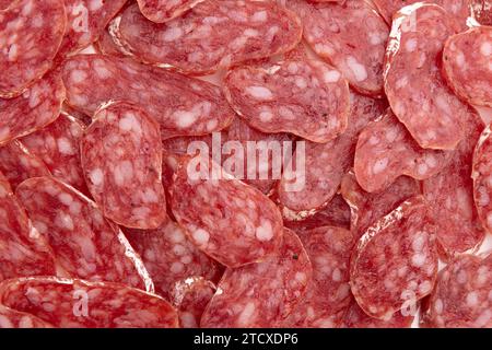 slices of salami as background, concept of tasty food with salami sausage, top view Stock Photo