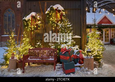 Christmas decorations - bench, Christmas trees, gift boxes, garlands and lights. Festive Christmas decoration at the Dome Square in old Riga city. Rig Stock Photo