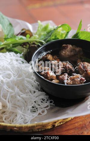 Hanoi-style bun cha with grilled pork and meatballs, vermicelli rice noodles, and fresh lettuce and herbs (mint, perilla leaf, coriander) Stock Photo