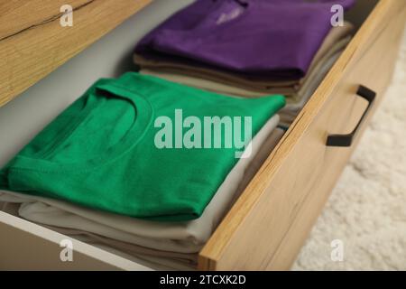 Stacks of different folded shirts in drawer indoors. Organizing clothes Stock Photo