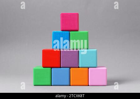 Pyramid of blank colorful wooden cubes on light grey background Stock Photo