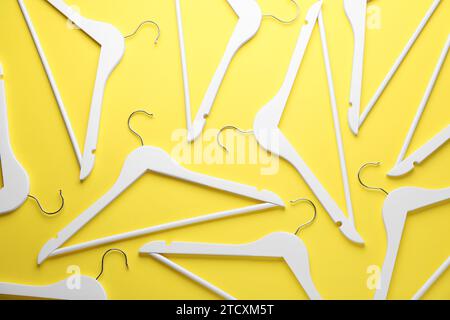 White hangers on yellow background, flat lay Stock Photo