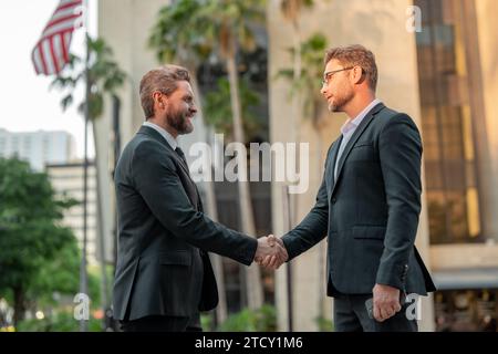 Business partners shaking hands. Businessmen in suit shaking hands outdoors. Handshake between two businessmen. wo business men had business contacts Stock Photo