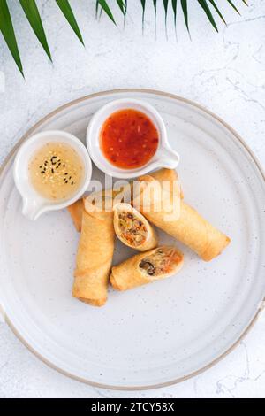 Crispy golden fried vegetable spring rolls with fresh ingredients served with soy and sweet and sour sauce in an oriental restaurant Stock Photo