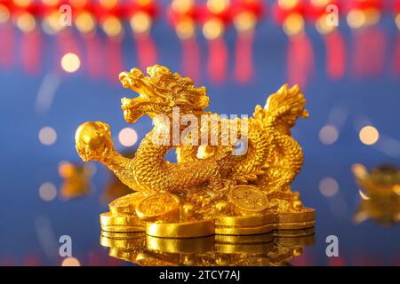 Golden Chinese dragon figurine on reflective surface against blue background, closeup Stock Photo