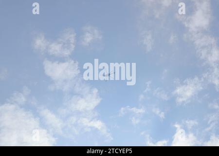 View of the underside of a helicopter flying under thin layers of white clouds under the blue sky Stock Photo