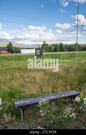 Serene lakeside view with wildflowers and a wooden bench in Grand Lake, Colorado. Stock Photo