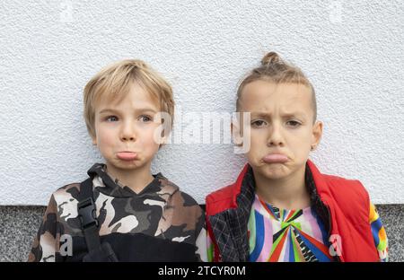 Two good offended boys of 7 years old with an offended expression on their faces, pursing their lips in displeasure Stock Photo