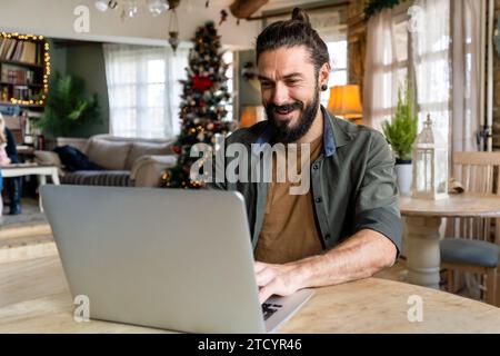 Young happy handsome hipster man using laptop at home. People online internet digital device concept Stock Photo