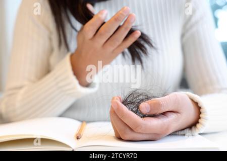 A woman suffering from alopecia holds her hair in her hands Stock Photo