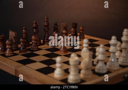 Chess pieces on a wooden board on a dark background Stock Photo