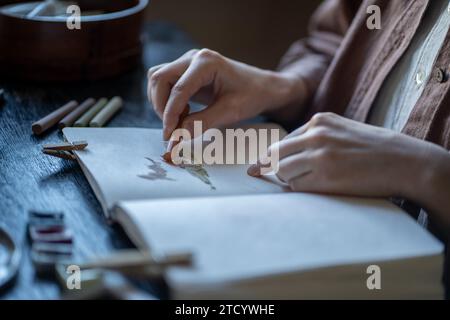 Illustrator art student painting sketches pastel crayons in sketchbook sitting at desk in art school Stock Photo