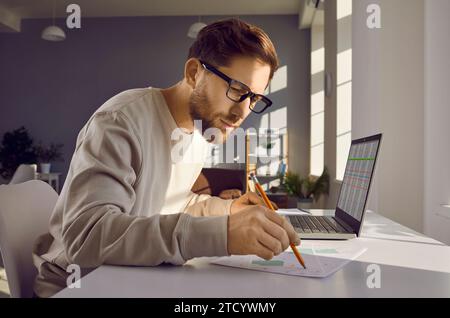 Professional cartographer working with printed cadastral map at table on his workplace. Stock Photo