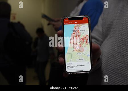 A person shows on his smartphone locations which are targeted by rockets attack from Gaza as he takes cover in a shelter at Ichilov Hospital which treated released hostages and continue to receive and treat wounded soldiers as the war with Hamas continues on December 11, 2023 in Tel Aviv, Israel. It has been more than two months since the Oct. 7 attacks by Hamas that prompted Israel's retaliatory air and ground campaign in the Gaza Strip. Stock Photo