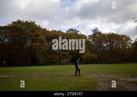 A lone walker makes her way across the golf course on Wimbledon Common during a late November flush of Autumn colou , London, England, UK Stock Photo