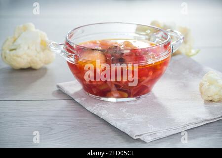 cooked vegetarian vegetable soup with mushrooms, cauliflower and other vegetables in a bowl on a light wooden table. Stock Photo