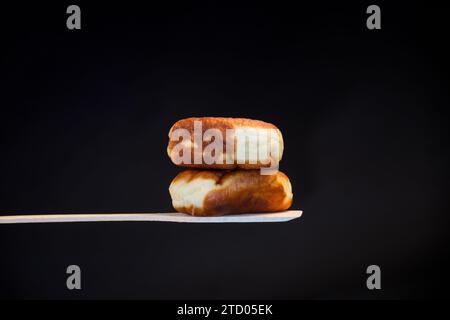 Fried pies filled with yeast dough on a wooden paddle, isolated on a black background. Ukrainian food. Stock Photo