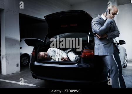 Man, kidnap and parking lot with phone call for ransom, negotiation and criminal with hostage, crime and danger. Gangster, mafia and scared person for Stock Photo