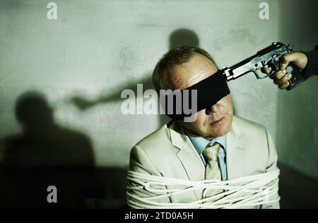 Man, abduction and hands with gun for crime, ransom and negotiation with terror, kidnap and danger at night. Criminal, scared person or hostage in Stock Photo