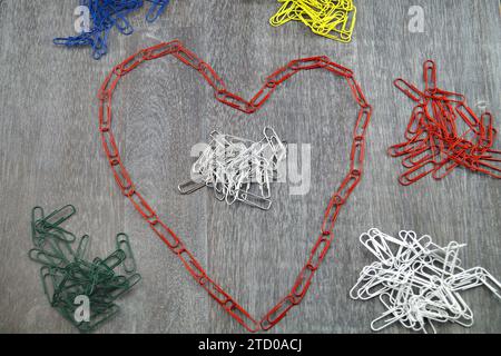 colourful paper-clips, the red layed in heart-shape, love in the office Stock Photo