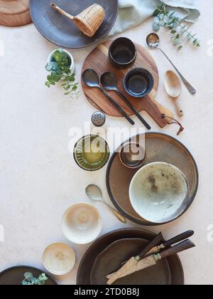 Top view of ceramic bowls with various different clean empty dinnerware and green herbs placed on white marble surface in modern restaurant Stock Photo