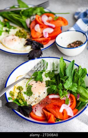 A ketogenic diet-friendly meal with poached eggs, fresh vegetables, and leafy greens served on a white and blue rimmed plate. Stock Photo