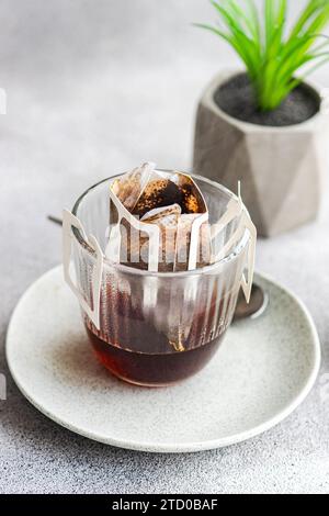A close-up image showcasing the process of making drip coffee with a paper filter placed inside a clear glass cup, which is set upon a ceramic saucer. Stock Photo