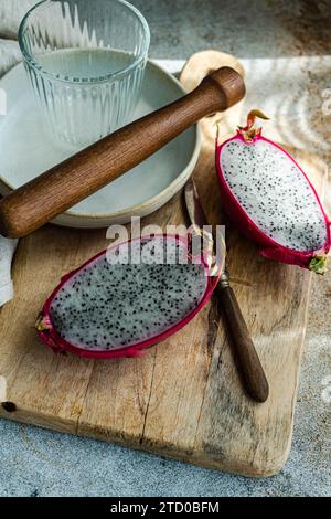 Sliced dragonfruit on a rustic wooden board with a rolling pin and ceramic plates. Stock Photo