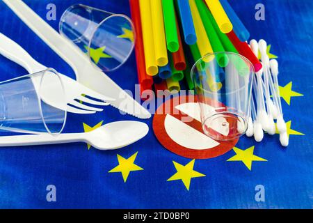 Plastic straws, cups, cutlery and cotton buds on European flag with prohibition ssign, ban on plastic in the EU Stock Photo
