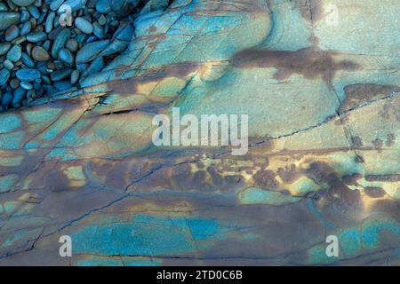 An abstract pattern of colorful rocks and pebbles with natural textures on a beach, ideal for backgrounds. Stock Photo