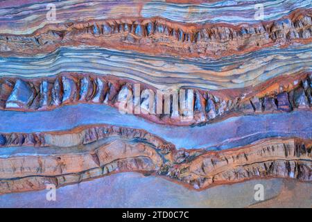 A close-up of vibrant, multi-colored sedimentary rock layers exhibiting natural stratification and weathering. Stock Photo
