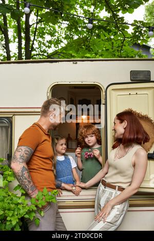 happy parents looking at daughter and son having fun in trailer home, family leisure and recreation Stock Photo