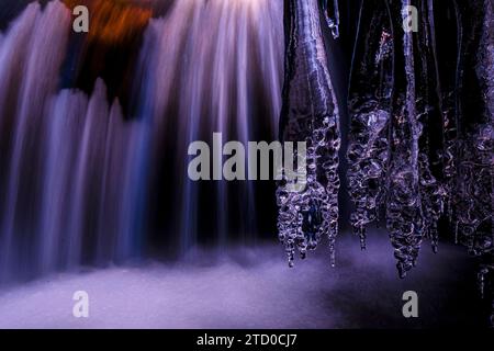 A close-up of delicate icicles forming against a softly blurred waterfall backdrop in Guadalajara Stock Photo