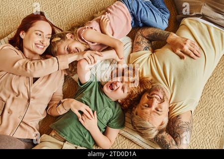 top view of happy parents and kids lying down and on floor and laughing in modern living room Stock Photo