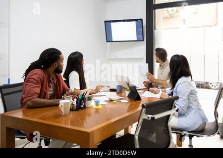 Multiracial businessmen and businesswomen discussing over monitor mounted on wall during presentation in boardroom at office Stock Photo