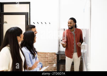 Smiling black businessman explaining to male and female colleagues during business meeting in office Stock Photo