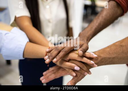 Crop hands of anonymous of multiracial male and female colleagues stacking hands together while standing in creative office Stock Photo