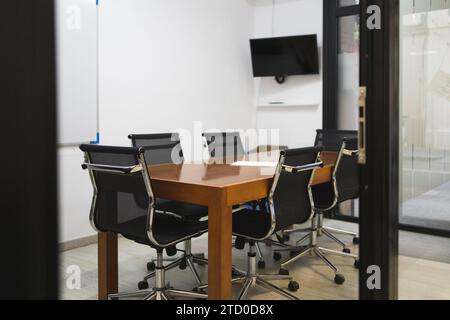 Interior of conference room with chairs arranged around wooden table in empty creative office seen through doorway Stock Photo