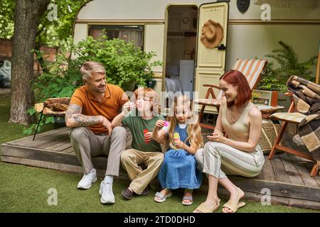 excited couple looking at children blowing soap bubbles near trailer home, leisure and fun Stock Photo