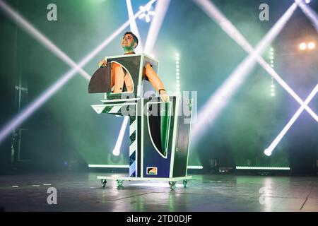 Male magician showing magic trick with half body in box on stage illuminated by spotlights during performance Stock Photo