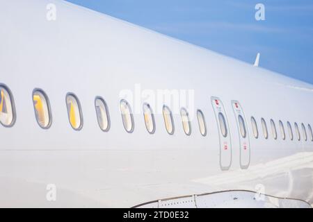 A perspective view from the wing of an airplane showing a row of cabin windows Stock Photo