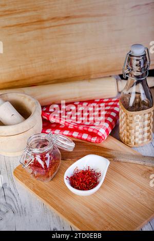 From above kitchen setup with a mortar and pestle, a checkered napkin, and saffron threads displayed on a white bowl and a glass jar, all arranged on Stock Photo