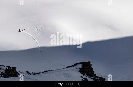 Aerial view of anonymous tourist snowboarding on majestic snow covered mountain slope during vacation in Zermatt, Switzerland on sunny day Stock Photo