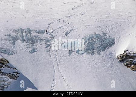 Aerial view of anonymous tourist snowboarding on majestic snow covered mountain slope during vacation in Zermatt, Switzerland on sunny day Stock Photo